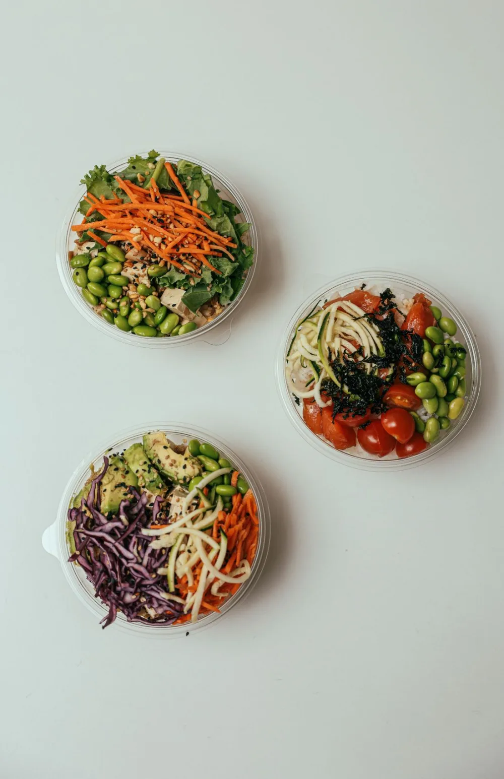 Fresh, colorful salad and grain bowls with vegetables, edamame, carrots, and avocado